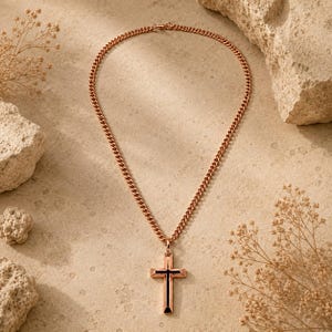 May include: A rose gold-toned metal curb chain necklace featuring a cross pendant. The cross pendant has a polished rose gold-toned frame with a smooth, solid black vertical inlay centered along the length of the cross bar and the vertical post.