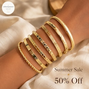 May include: A set of seven gold-toned metal bangles featuring various textures and patterns, including twisted rope, star motifs, heart shapes, and geometric engravings. The text Summer Sale 50% Off is visible in the lower right corner of the image.
