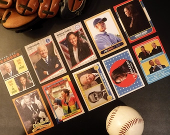 May include: A collection of baseball cards featuring images of Joe Biden and Kamala Harris. The cards are arranged in a grid pattern on a black surface. A baseball is in the lower right corner of the image.
