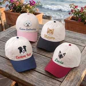 May include: Four baseball caps with white crowns and colored brims. One has a white dog and 'Custom Embroidery', one a ginger cat and 'Mauro', one a black and white dog and 'Custom Text', and one a Siamese cat and 'Lucia' embroidered on the front.