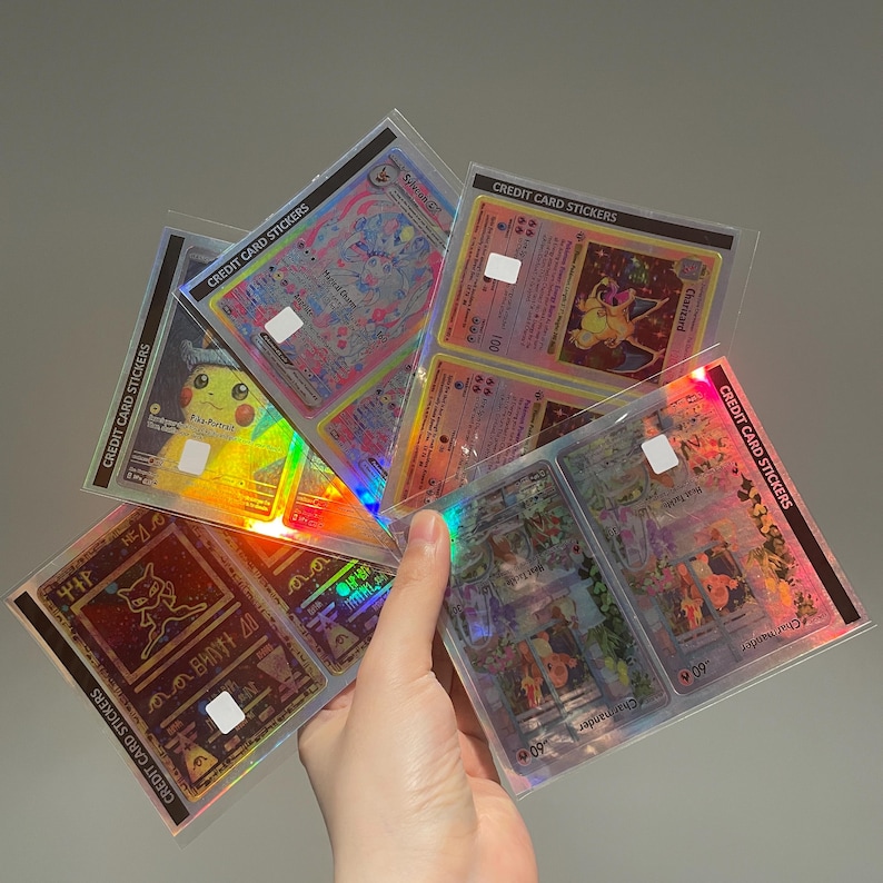Puede incluir: Una colecci&oacute;n de cartas coleccionables hologr&aacute;ficas, con varios personajes y dise&ntilde;os. Las cartas est&aacute;n en fundas protectoras, con el texto "CREDIT CARD STICKERS" visible. Las cartas tienen un acabado brillante e iridiscente.