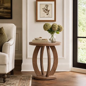 May include: A round wooden side table with a textured light brown finish, featuring a base composed of three curved, arching legs connected to a circular pedestal. On top sits a clear glass vase with green hydrangea flowers and a book.