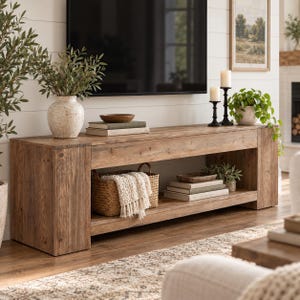 May include: A rectangular wooden media console featuring a natural wood grain finish, a wide top surface, and an open lower shelf. The console is constructed with thick side panels and a sturdy base, providing a stable platform for storage and display.