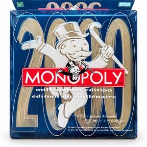 May include: A Monopoly Millennium Edition board game box featuring a metallic blue background with large gold 2000 numerals. A white embossed figure of Rich Uncle Pennybags holding a cane is centered over a red Monopoly logo with white text.