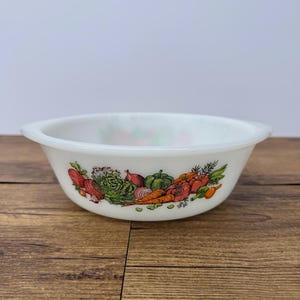 May include: A white milk glass bowl featuring a colourful wrap-around illustration of various fresh vegetables including carrots, tomatoes, lettuce, and onions. The bowl has a smooth, rounded rim and a wide, shallow basin design for serving.