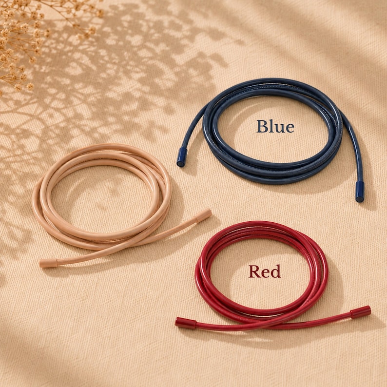 Op de afbeelding: Drie opgerolde koorden in beige, blauw en rood. Elk koord is voorzien van bijpassende eindkappen. Het blauwe koord is gelabeld met de tekst Blue en het rode koord met de tekst Red. Deze flexibele koorden zijn gerangschikt in cirkelvormige lussen.