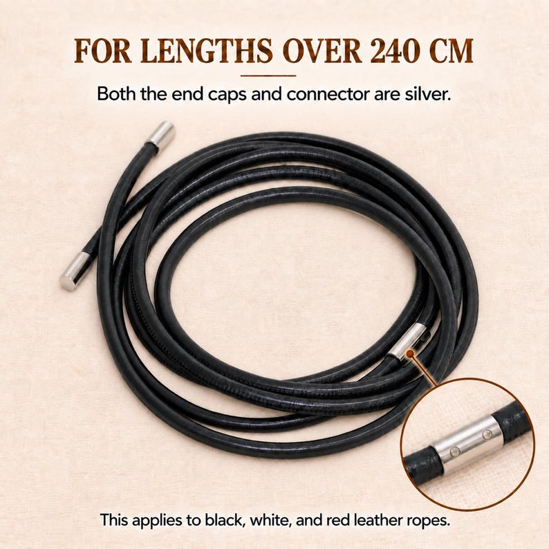 Op de afbeelding: Een opgerold zwart leren touw met zilveren eindkappen en een zilveren connector. De tekst luidt: FOR LENGTHS OVER 240 CM. Both the end caps and connector are silver. This applies to black, white, and red leather ropes.