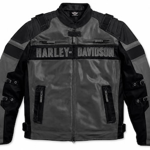 Könnte beinhalten: Eine schwarz-graue Motorradjacke mit dem Schriftzug HARLEY-DAVIDSON auf der Brust. Die Jacke verfügt über einen Stehkragen, einen durchgehenden Frontreißverschluss, zwei Brusttaschen mit Reißverschluss, zwei untere Reißverschlusstaschen und verstellbare Riemen.