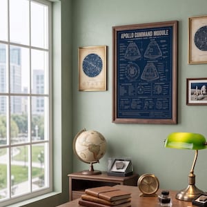 May include: A framed dark blue technical print titled APOLLO COMMAND MODULE featuring white line drawings and text detailing the spacecraft components, displayed on a wall alongside other framed prints, a globe, and a desk lamp.