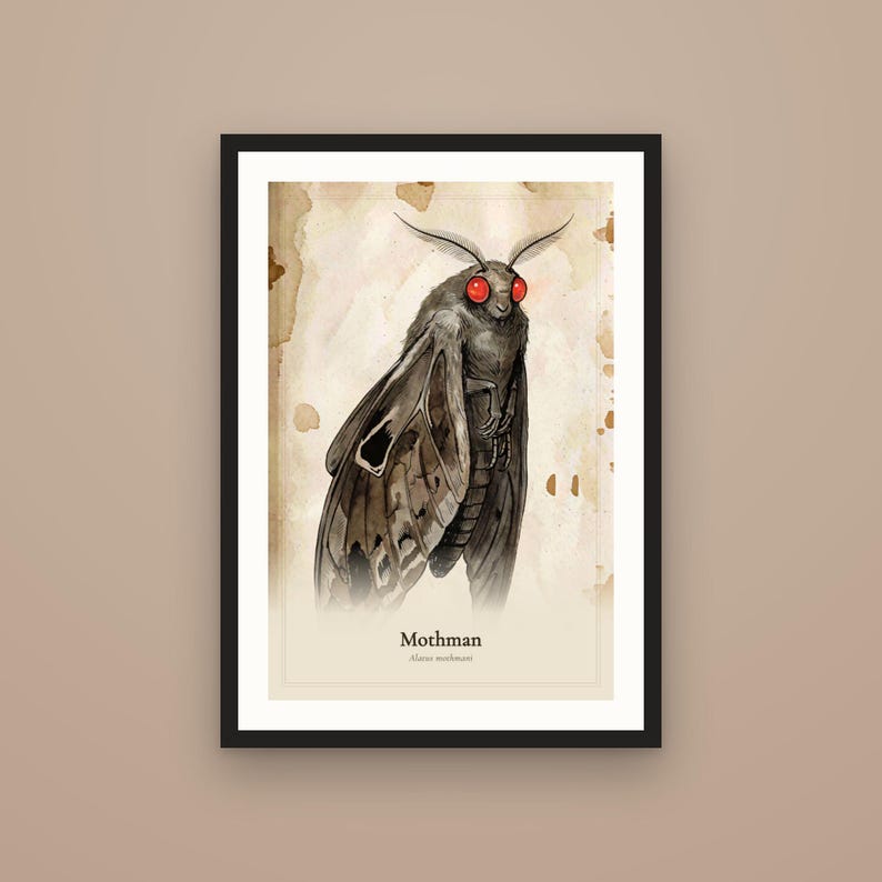 Op de afbeelding: Een ingelijste kunstdruk met een donker, gevleugeld wezen met gloeiende rode ogen, gelabeld als Mothman en Alarus mothmani. De illustratie staat op een lichte, perkamentachtige achtergrond met bruine inktvlekken en een dunne zwarte rand.