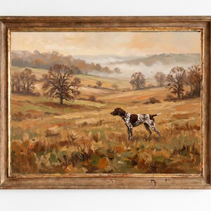 May include: Oil painting of a dog in a field, set in a rustic, gold-toned wooden frame. The dog is brown and white, standing in a grassy field with trees and rolling hills in the background. The artwork has a vintage aesthetic.