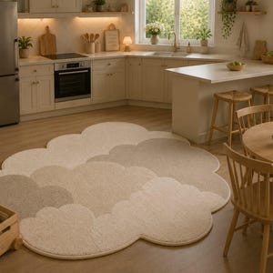 Peut inclure: Un grand tapis en forme de nuage avec une texture touffetée douce dans des tons neutres de crème, beige et taupe clair. Le tapis présente un bord festonné distinct qui suit les formes arrondies et superposées des nuages sur toute sa surface.
