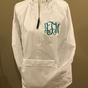 May include: White hooded jacket with a zipper and a teal monogram on the front. The jacket has a kangaroo pocket on the front.