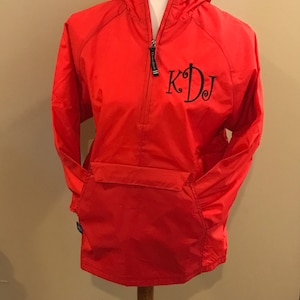 May include: Red hooded jacket with a zipper closure and a large black monogram "KDJ" on the front.