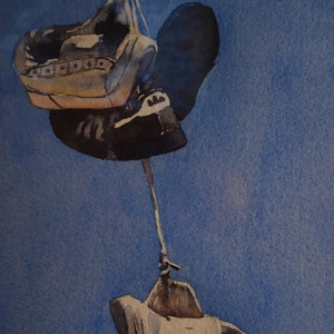May include: Three pairs of shoes hang from a string against a blue background. The shoes are a mix of brown, black, and white.
