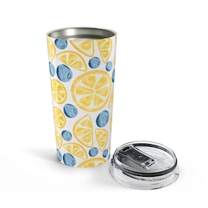 Op de afbeelding: Een roestvrijstalen beker met een aquarelpatroon van gele citroenschijfjes en blauwe bosbessen op een witte achtergrond, vergezeld van een doorzichtig, afneembaar plastic deksel met een schuifmechanisme voor de drinkopening.