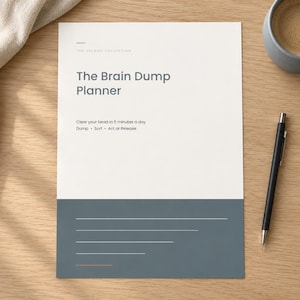 May include: A white and dark gray planner page titled The Brain Dump Planner with the text Clear your head in 5 minutes a day, Dump, Sort, Act or Release, and several horizontal lines for writing, accompanied by a black pen and a coffee mug.