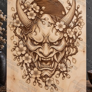 Può includere: Una targa rettangolare in legno con un'illustrazione incisa al laser di una maschera Hannya circondata da rami di ciliegio in fiore e un motivo solare circolare scuro. L'opera presenta ombreggiature dettagliate su legno chiaro.