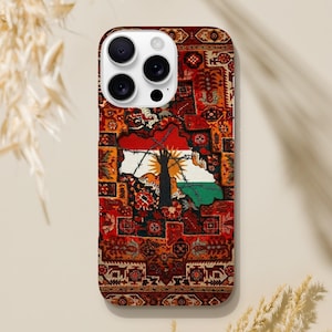 Könnte beinhalten: Eine Handyhülle mit einem lebendigen Muster, das an einen traditionellen Teppich erinnert. Das Design zeigt eine Kartenkontur mit einem Baum- und Flaggenmotiv in der Mitte, vor einem Hintergrund aus roten, orangefarbenen und braunen Farbtönen.