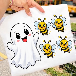 May include: A white fabric item featuring a large, cheerful cartoon ghost with black eyes and a wide smile, positioned next to four small, smiling yellow and black striped bees with light blue wings, all rendered in a bright, colorful graphic style.