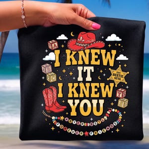 May include: A black t-shirt featuring a graphic print with the text I KNEW IT I KNEW YOU, a red cowboy hat, red cowboy boots, alphabet blocks, a sheriff star badge labeled EST. BESTIE 4EVA, and a beaded necklace with the text FOREVER FRIENDS.