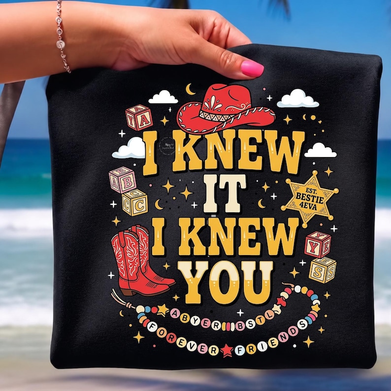 May include: A black t-shirt featuring a graphic print with the text I KNEW IT I KNEW YOU, a red cowboy hat, red cowboy boots, alphabet blocks, a sheriff star badge labeled EST. BESTIE 4EVA, and a beaded necklace with the text FOREVER FRIENDS.
