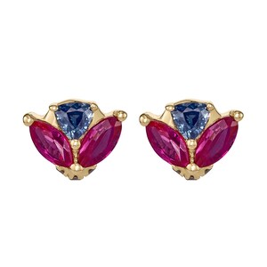 May include: A pair of gold-toned stud earrings. Each earring features a central blue gemstone, flanked by two fuchsia-colored gemstones. The gemstones are set in a fan-like arrangement.