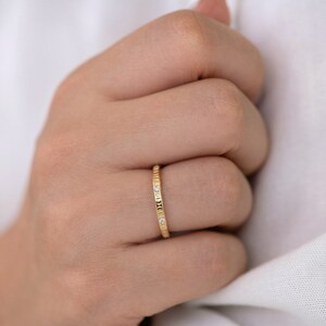 Puede incluir: Un fino anillo de banda de oro con peque&ntilde;os diamantes engastados en la banda.