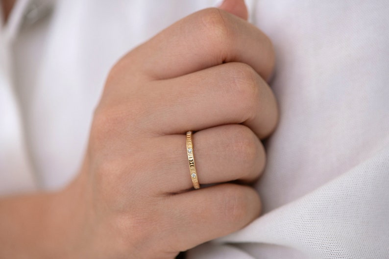 Puede incluir: Un fino anillo de banda de oro con peque&ntilde;os diamantes engastados en la banda.