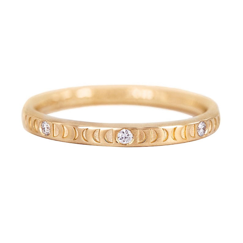 Puede incluir: Un anillo de banda de oro con un dise&ntilde;o de luna creciente y tres peque&ntilde;os diamantes.