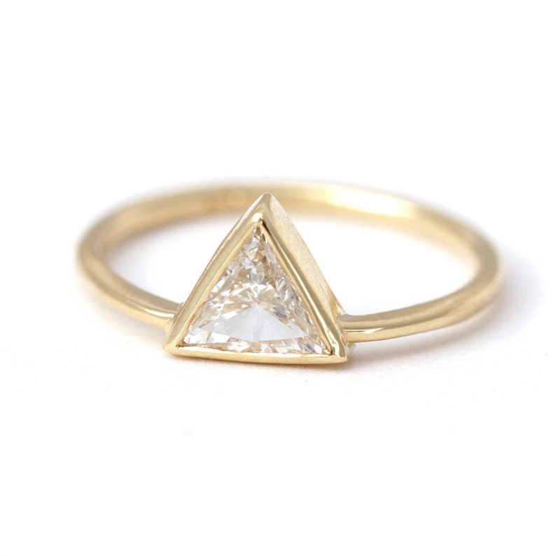 May include: A gold ring with a triangular shaped diamond set in a bezel setting.