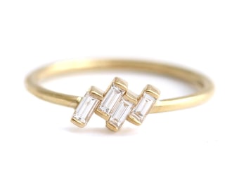 May include: A delicate gold band ring with a cluster of five baguette-cut diamonds set in a staggered pattern.