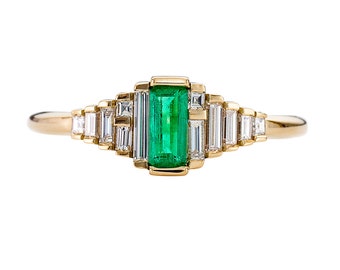 Delicado anillo de compromiso de esmeralda con diamantes talla baguette.
