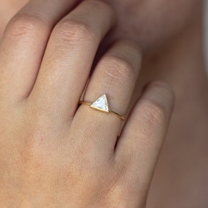 May include: A gold ring with a triangular shaped diamond.