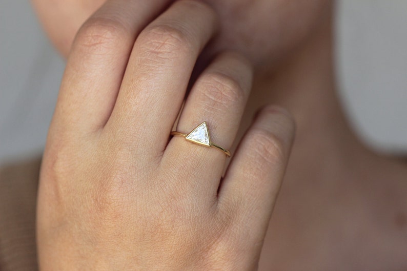 May include: A gold ring with a triangular shaped diamond.