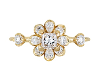 May include: A gold ring with a square-shaped diamond in the center, surrounded by smaller diamonds set in a flower-shaped design.