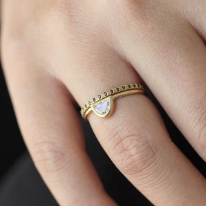 May include: A gold ring set with a half-moon shaped diamond and a thin band of black diamonds.