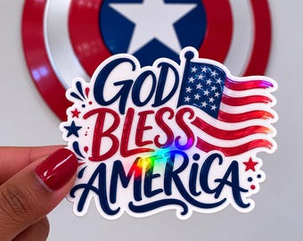 May include: A patriotic sticker with the text "GOD BLESS AMERICA" in red and blue, featuring an American flag design. The sticker has a holographic effect and is decorated with stars.