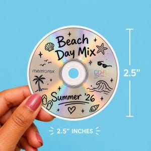 May include: A circular CD-R disc with a holographic finish, measuring 2.5 inches in diameter. The surface features black line art of a palm tree, seashell, starfish, wave, sunglasses, and flip-flops, with the text Beach Day Mix Summer '26.