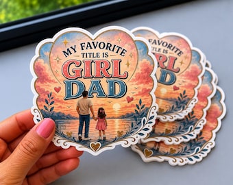 May include: A heart-shaped sticker featuring a sunset landscape with a parent and child holding hands by the water. The text reads MY FAVORITE TITLE IS GIRL DAD in bold blue and pink lettering. The design includes decorative floral accents.