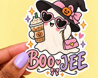 May include: A die-cut vinyl sticker featuring a white ghost wearing a black witch hat with a pink bow and orange pumpkin, heart-shaped sunglasses, and holding a coffee cup with a pumpkin icon. A pink quilted purse and the text BOO-JEE are included.