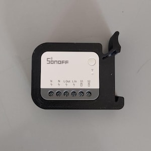 Può includere: Un dispositivo per la casa intelligente Sonoff nero con un pannello centrale bianco. Il pannello presenta il logo Sonoff, un pulsante e indicatori di connessione. Il dispositivo ha porte di connessione etichettate N, Lout, L, S1 e S2.