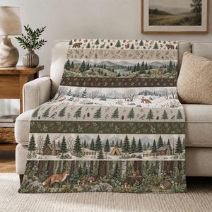 Könnte beinhalten: Eine Wohndecke mit horizontalen Streifen, die Waldlandschaften zeigen, darunter Illustrationen von Tannen, Bergen, Hütten, einem Zelt und Waldtieren wie Füchsen, Bären und Eichhörnchen in gedeckten Grün-, Braun- und Cremetönen.