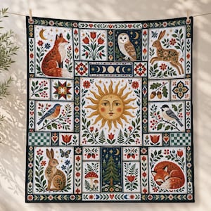 May include: A rectangular quilt featuring a central sun illustration surrounded by panels of foxes, rabbits, an owl, birds, flowers, mushrooms, and a pine tree. The design uses a palette of red, orange, green, and blue on a cream background.