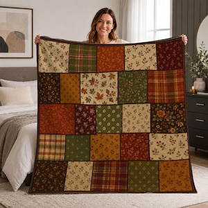 Könnte beinhalten: Eine Patchwork-Decke mit einem Raster aus quadratischen Stoffbahnen in herbstlichen Farben wie Dunkelrot, Waldgrün, Senfgelb und Creme. Das Design umfasst verschiedene Muster wie Karos, florale Drucke und Ahornblätter.