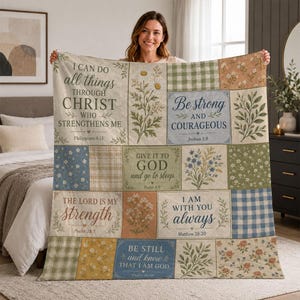 May include: A quilted throw blanket featuring a patchwork design of floral patterns, gingham checks, and text panels. The text includes Bible verses such as I Can Do All Things Through Christ, Be Strong and Courageous, and The Lord Is My Strength.