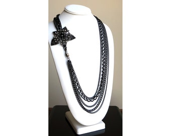 Gun metal multi-strand necklace with focal crystal adorned flower and large clip closure