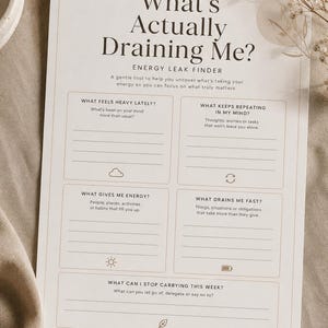 Può includere: Un foglio di carta bianco intitolato "What's Actually Draining Me?" con suggerimenti per identificare le perdite di energia. Il testo include "Energy Leak Finder" e suggerimenti come "What Feels Heavy Lately?" e "What Gives Me Energy?"