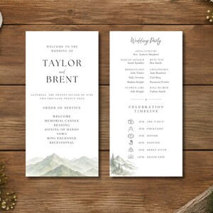 Könnte beinhalten: Eine zweiseitige weiße Hochzeitskarten-Programmkarte mit schwarzem Serifentext und einer Aquarell-Berglandschaft am unteren Rand. Die linke Seite zeigt die Namen des Paares, Taylor und Brent, sowie den Ablauf. Die rechte Seite listet die Hochzeitsgesellschaft und den Zeitplan.