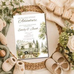 Könnte beinhalten: Eine rechteckige Einladungskarte für eine Babyparty mit dem Text Our Greatest Adventure, Emily & Jacob sowie Veranstaltungsdetails. Das Design zeigt eine Aquarellillustration eines Vintage-Wohnwagens, Kiefern und Grünpflanzen.